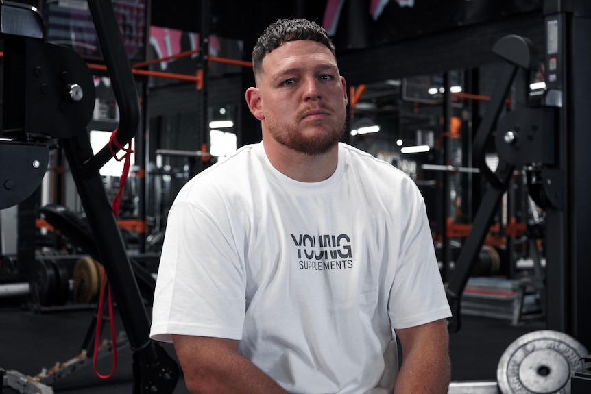 a rugby league player sitting on a bench at a gym.