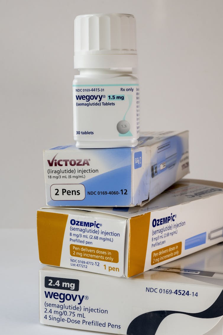 Bottle of oral Wegovy tablets sits atop three boxes of injectable GLP-1 drugs.