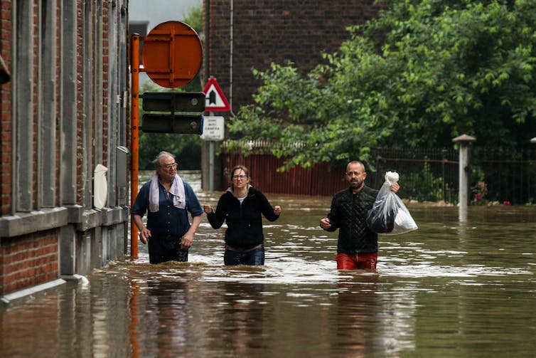 People walk through flooded street