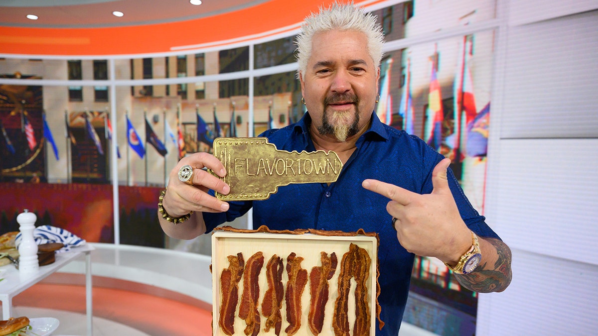 Guy Fieri on Today Show set with Flavortown key and tray of bacon.