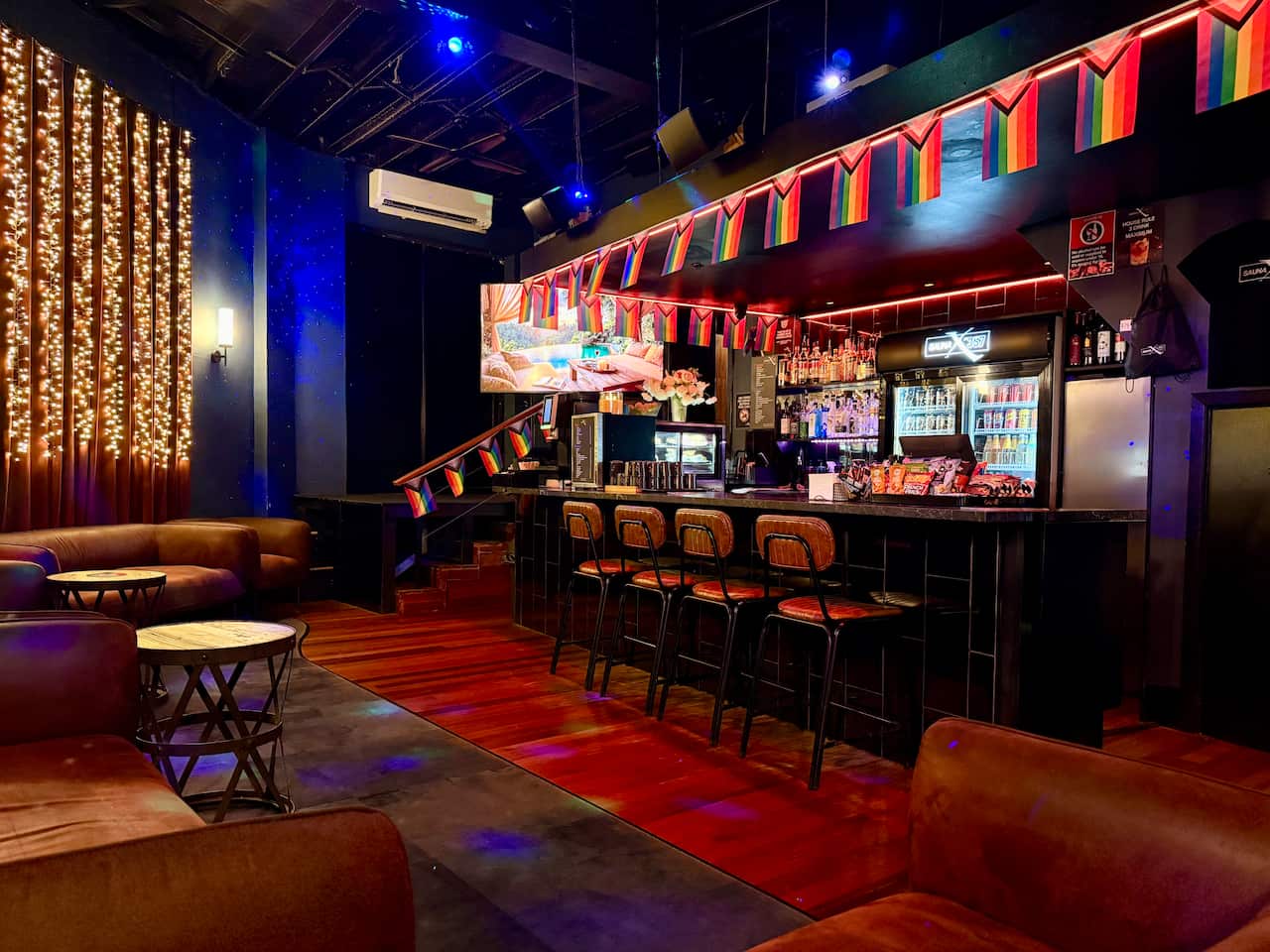 An interior shot of the bar inside Sauna X by 357, lined with rainbow Pride flags.