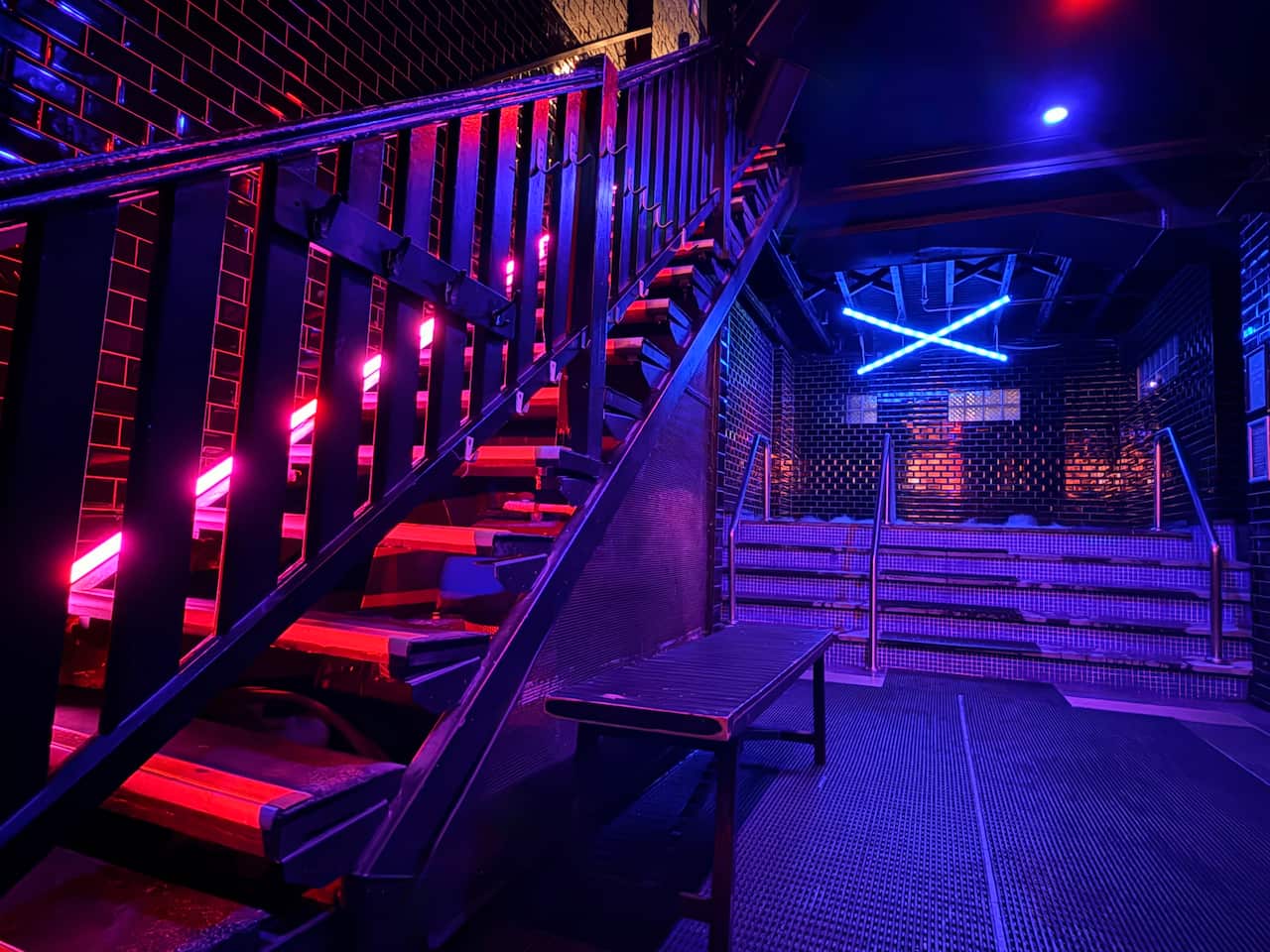 An interior shot of a neon-lit staircase inside Sauna X by 357.