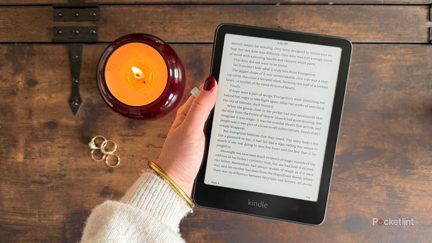 A candle and rings beside an e-reader.