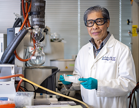 Man with white coat in lab holding specimen.