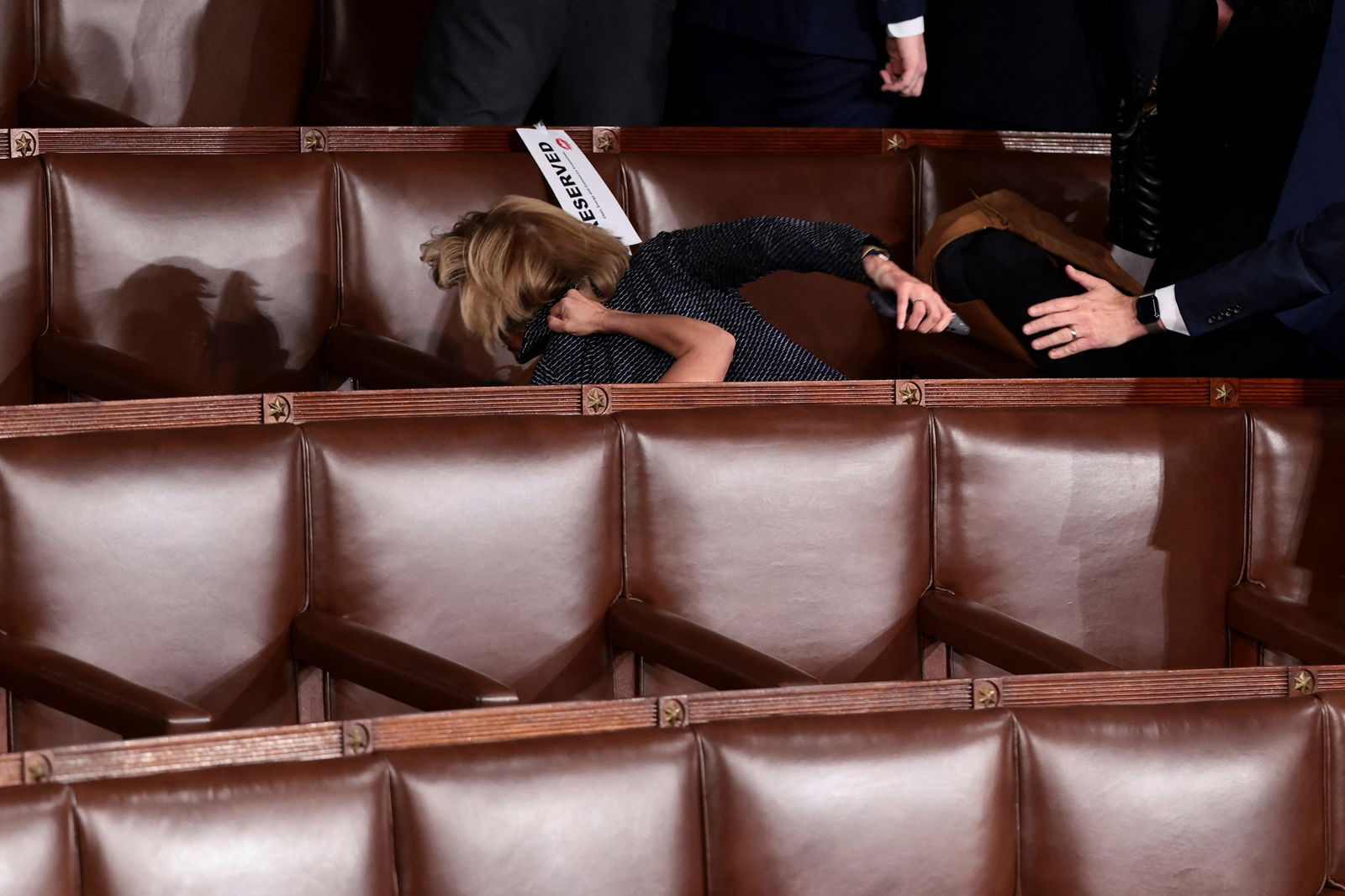 lauren boebert's arm appears over the chairs as she pulls down claudia tenney