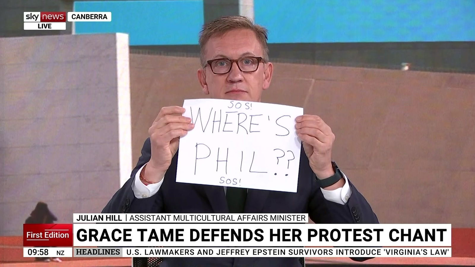 A TV screenshot of a man holding up a sign saying "Where's Phil??"