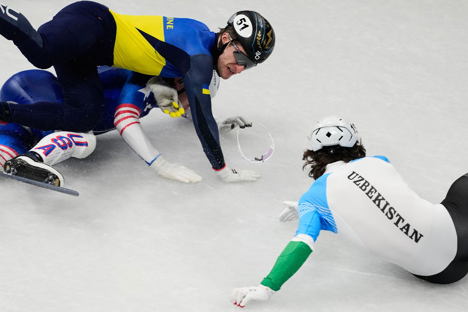 Brandon Kim of the United States, Oleh Handei of Ukraine and Daniil Eybog of Uzbekistan crash in the heats during the men's 500 meter short track speed skating at the 2026 Winter Olympics, in Milan, Italy, Monday, Feb. 16, 2026.