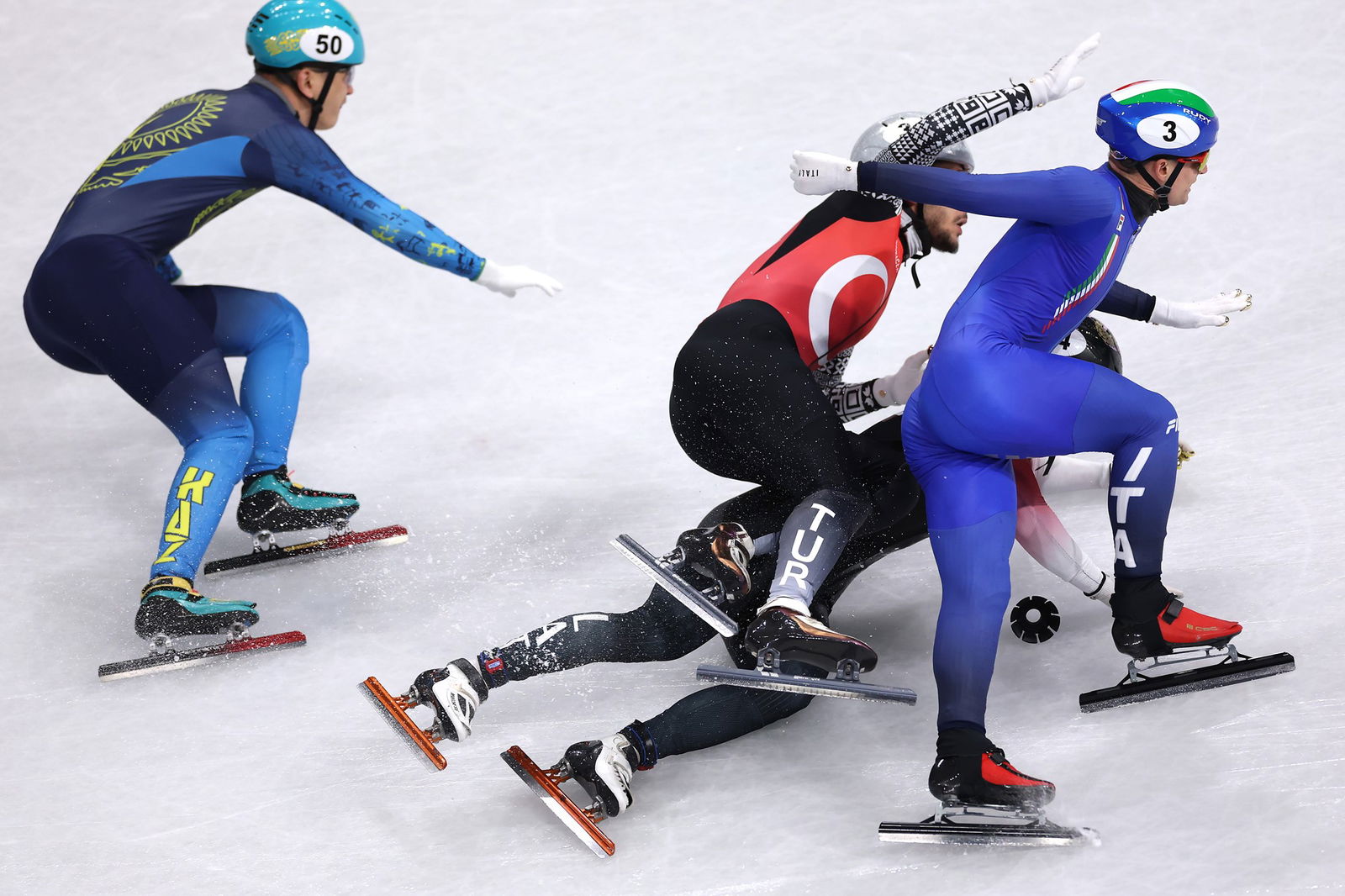 Pietro Sighel of Team Italy, Furkan Akar of Team Türkiye and Reinis Berzins of Team Latvia crash in heat 2 of the Short Track Speed Skating Men's 500m on day ten of the Milano Cortina 2026 Winter Olympic games at Milano Ice Skating Arena on February 16, 2026 in Milan, Italy.