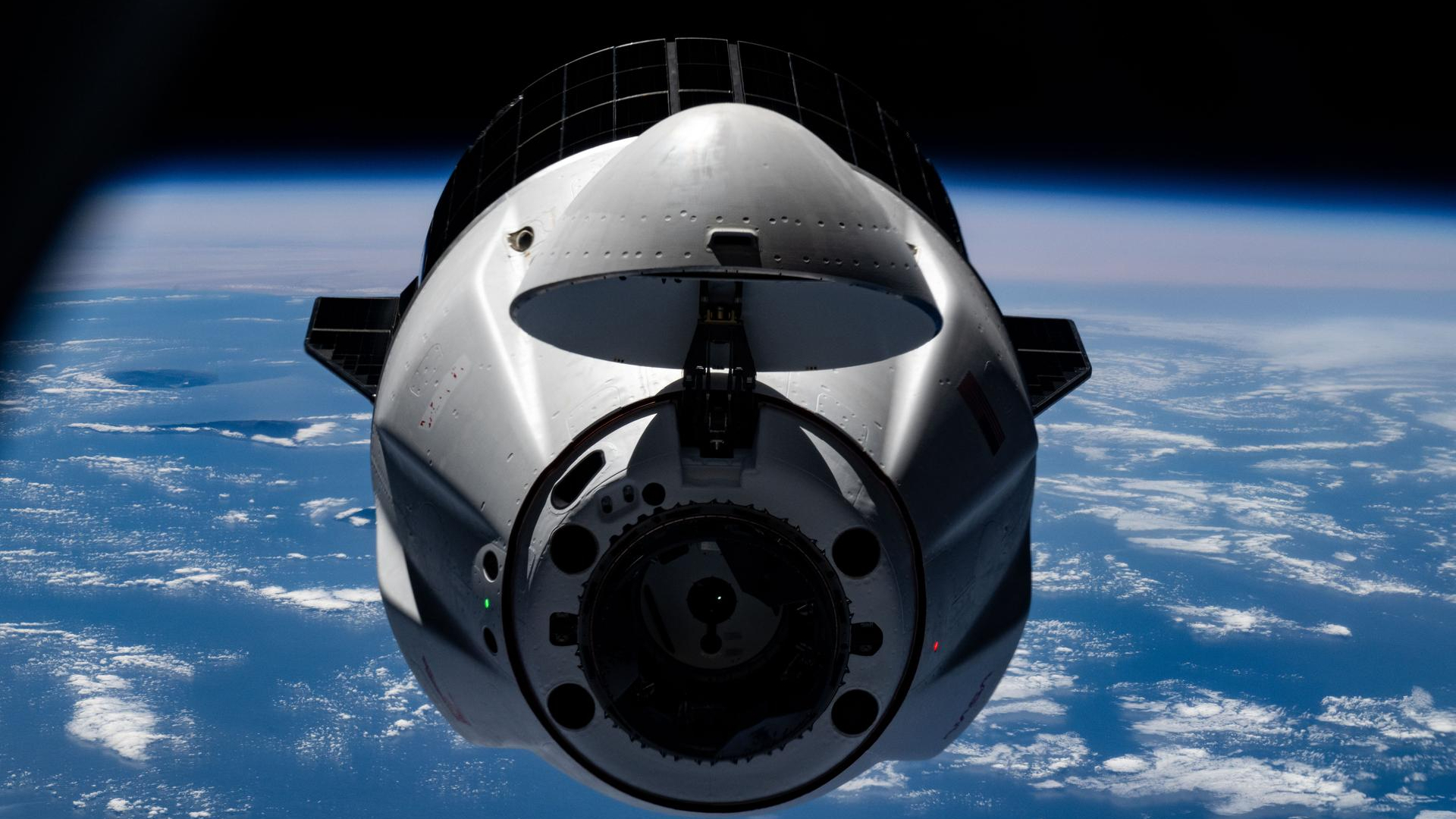 closeup, front-on view of a conical white space capsule with earth in the background