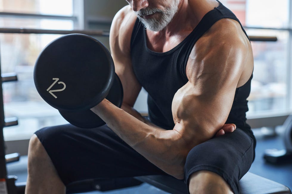 Man with dumbbell strengthening biceps in gym man with dumbbell strengthening biceps in gym