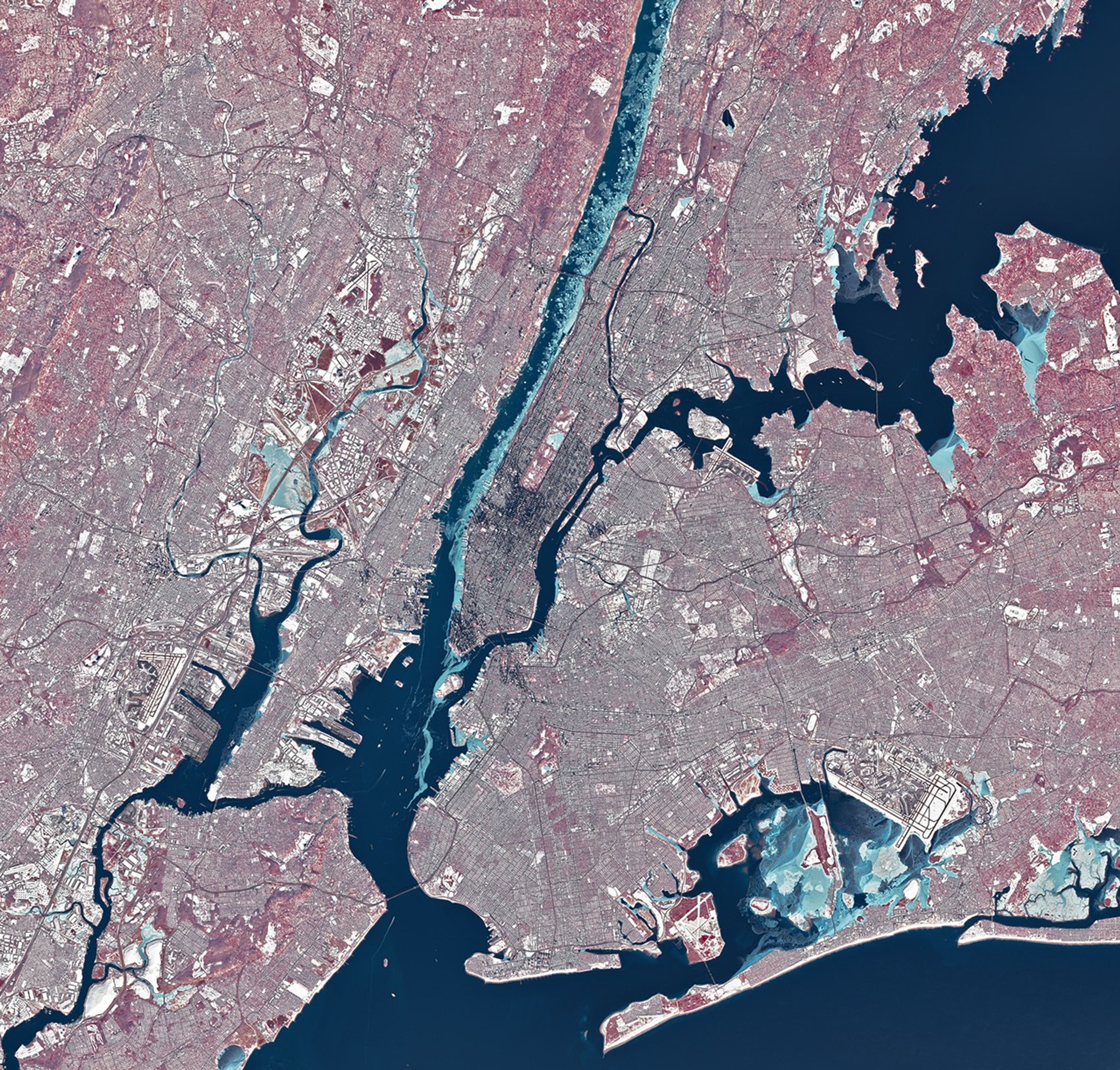Chunks of ice, which appear light blue in this false-color image, line the western shore of Manhattan in the Hudson River. Smaller rivers and lakes in the scene also appear frozen or partially frozen. The ground is snow-covered, and tall buildings cast long, dark shadows.