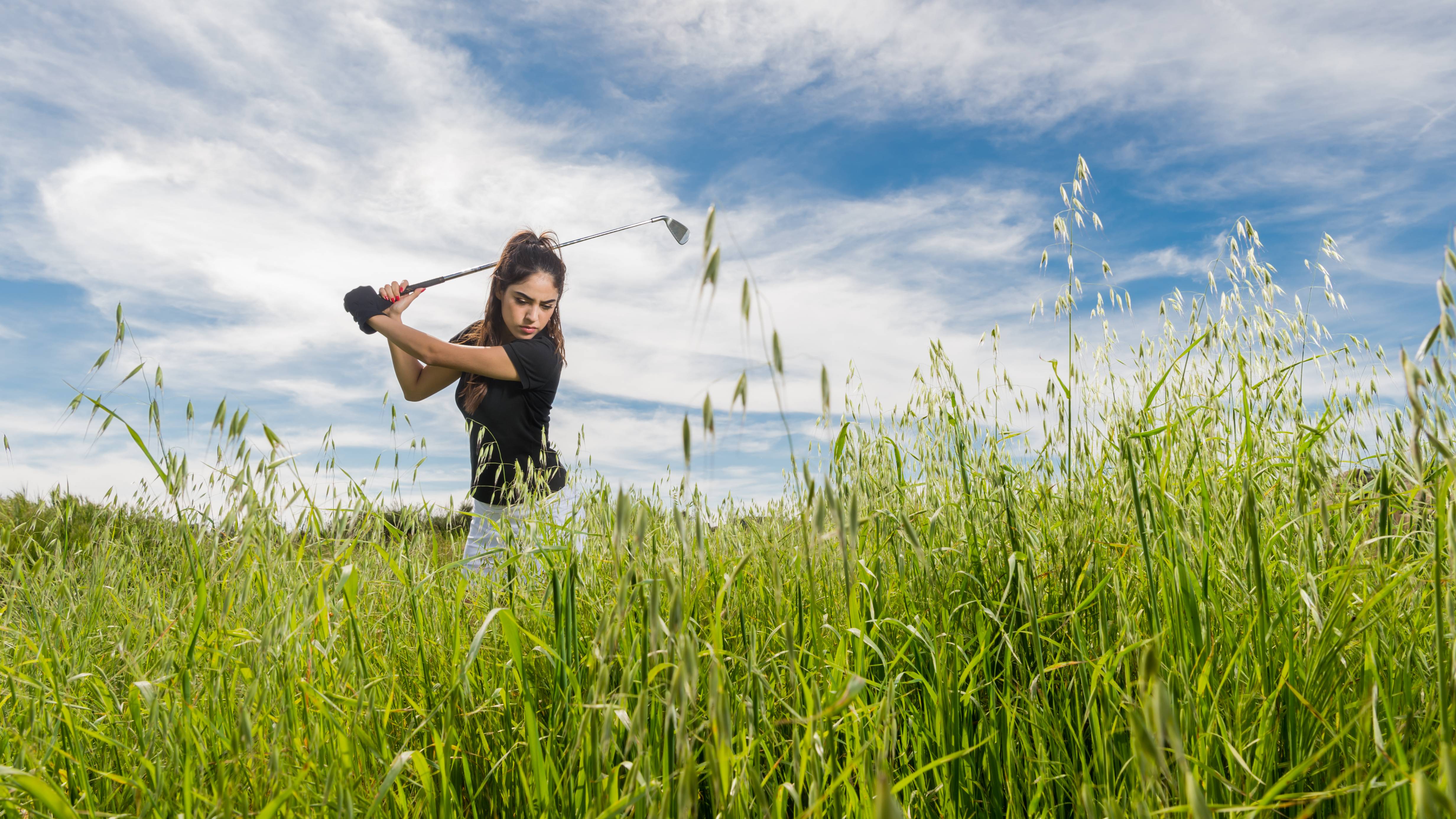 Female golfer hitting out of the rough