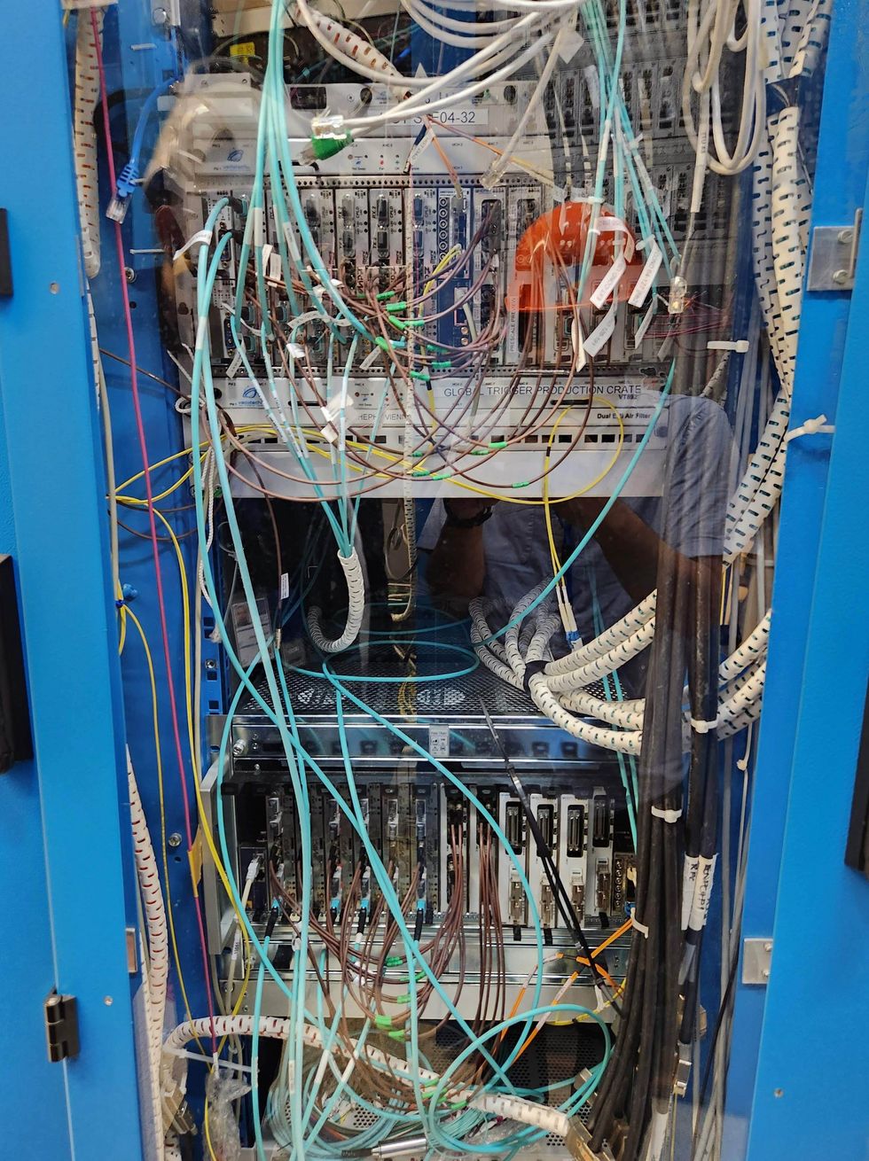 Photo show rows of electronic racks filled with cables and equipment inside a data-acquisition room.