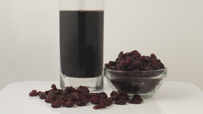 Dried cherries next to a glass of juice