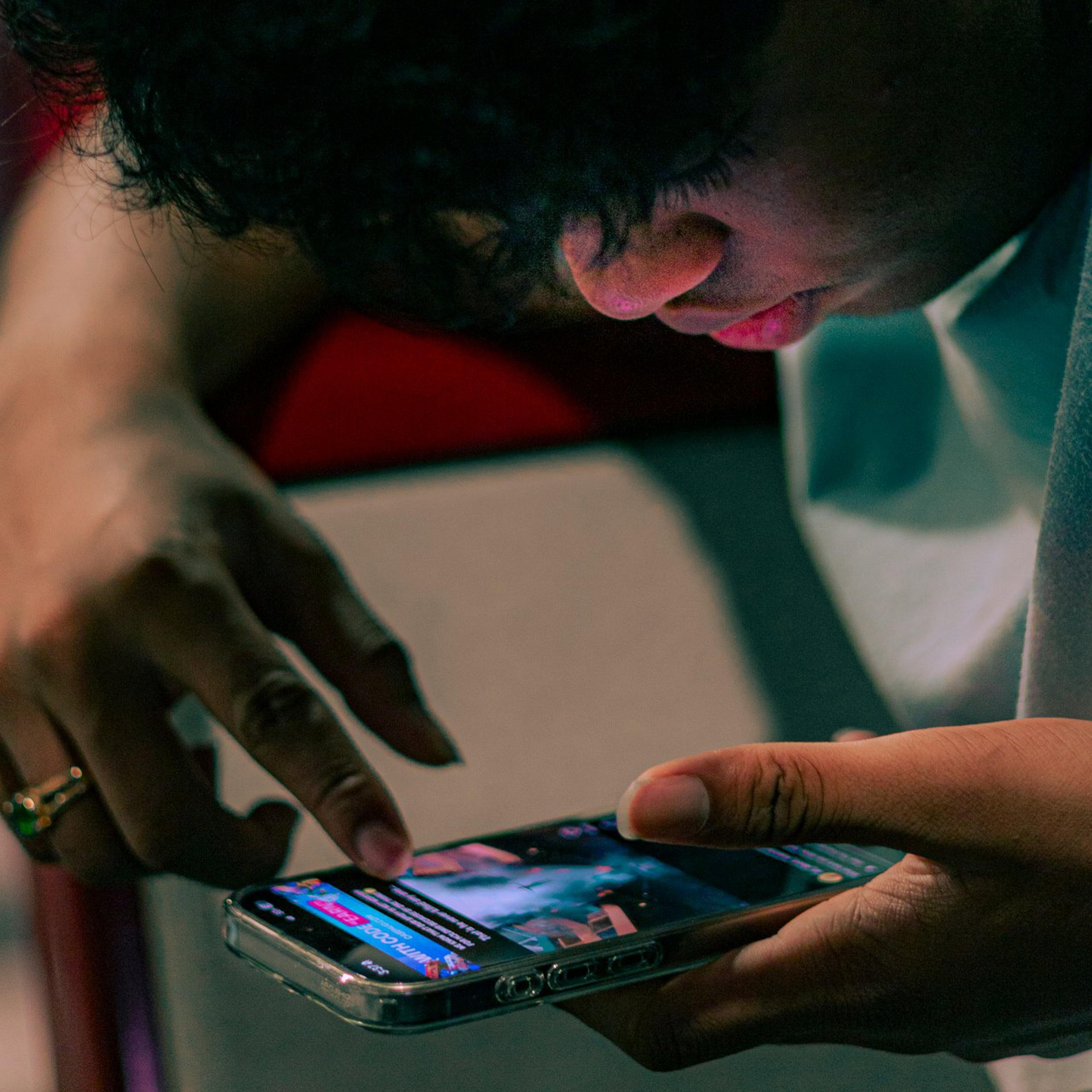 A person using a smartphone, with focus on their finger scrolling the screen. Face partially visible.