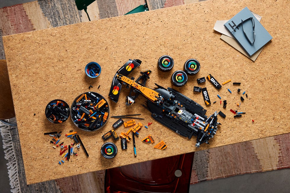 a workspace displaying a partially assembled toy racing car with scattered building pieces