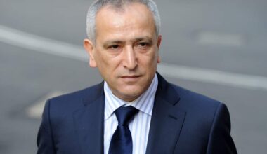 A man in a dark suit blue with a light shirt and a dark blue tie