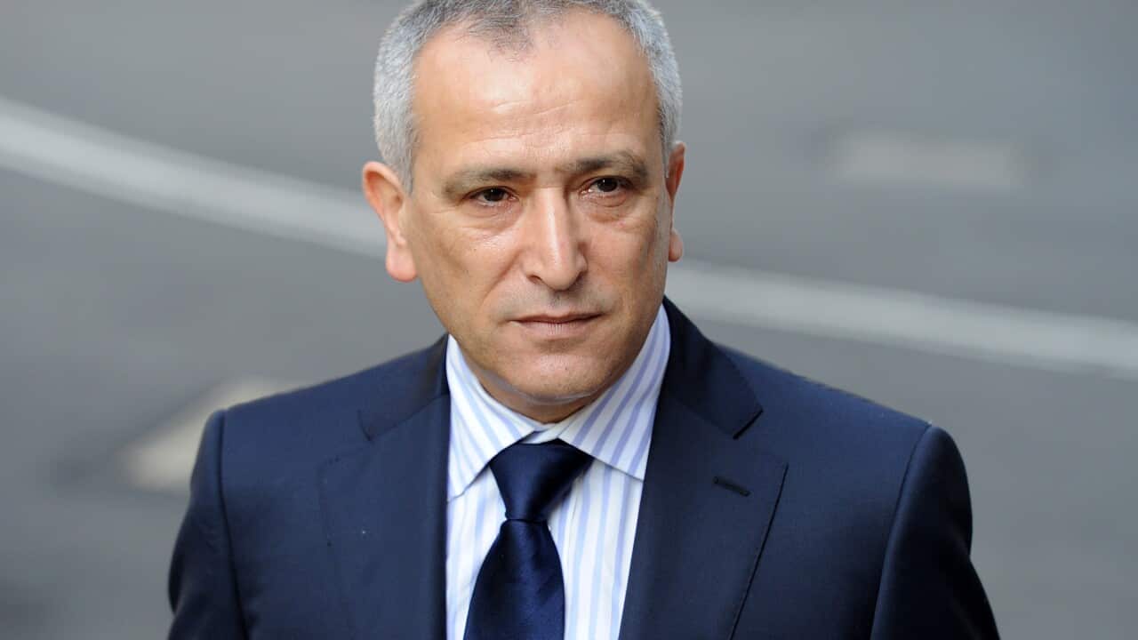 A man in a dark suit blue with a light shirt and a dark blue tie