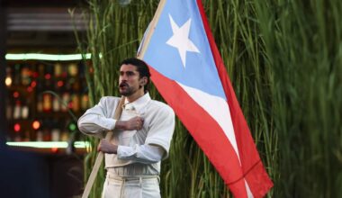 A man holding a Puerto Rican flag in front of long grass.