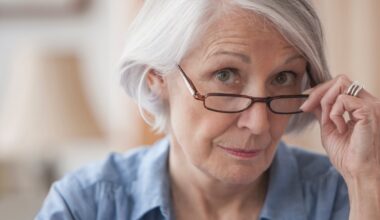 A person holding eyeglasses on the bridge of the nose.