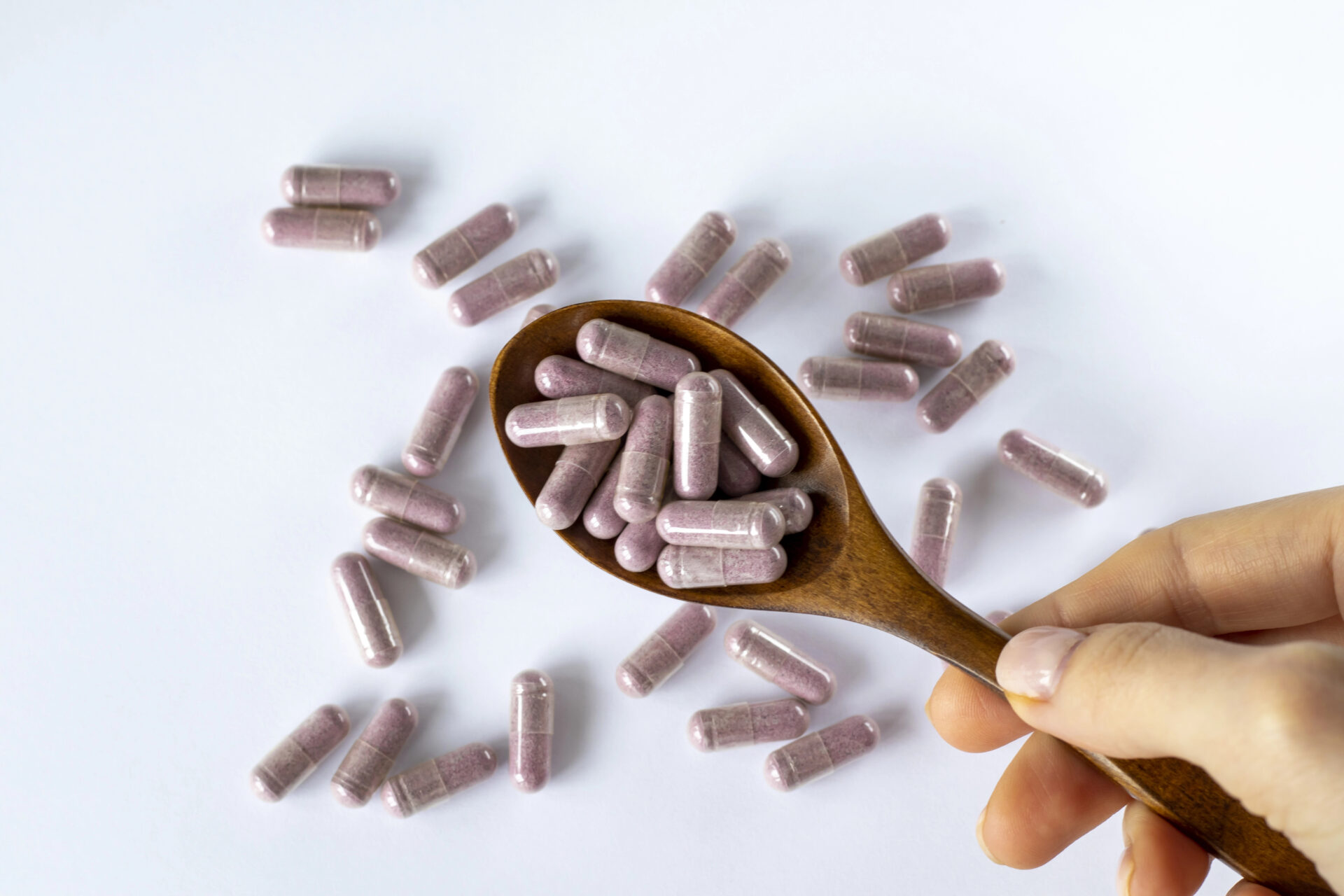 purple Women's Multivitamins on a wooden spoon