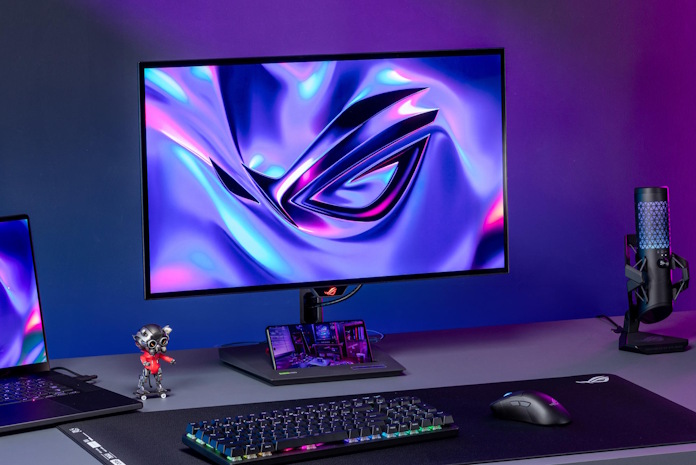 A gaming setup on a desktop with the ROG Swift OLED PG27ACDNG at the center