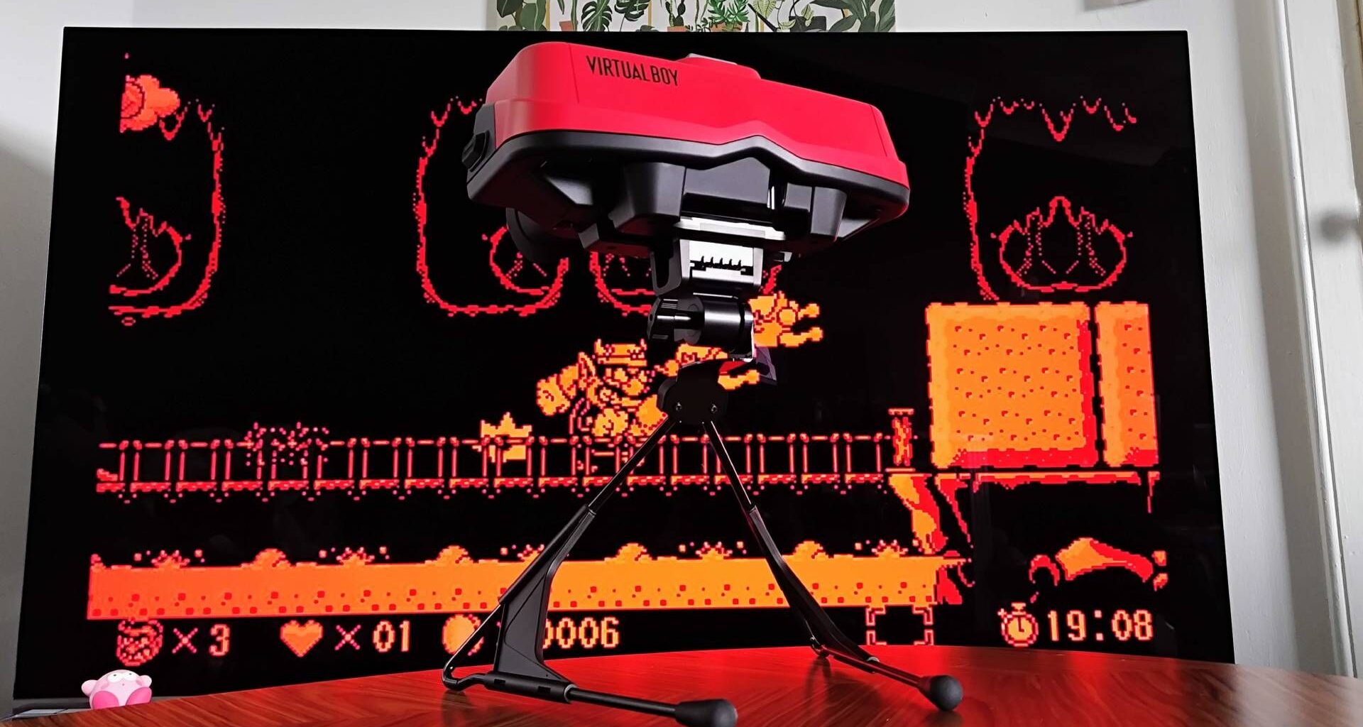 Switch Virtual Boy on woodgrain table with TV in backdrop and Virtual Boy Wario Land on screen.