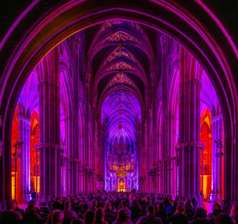 A group of people in a large room with arches and columns.