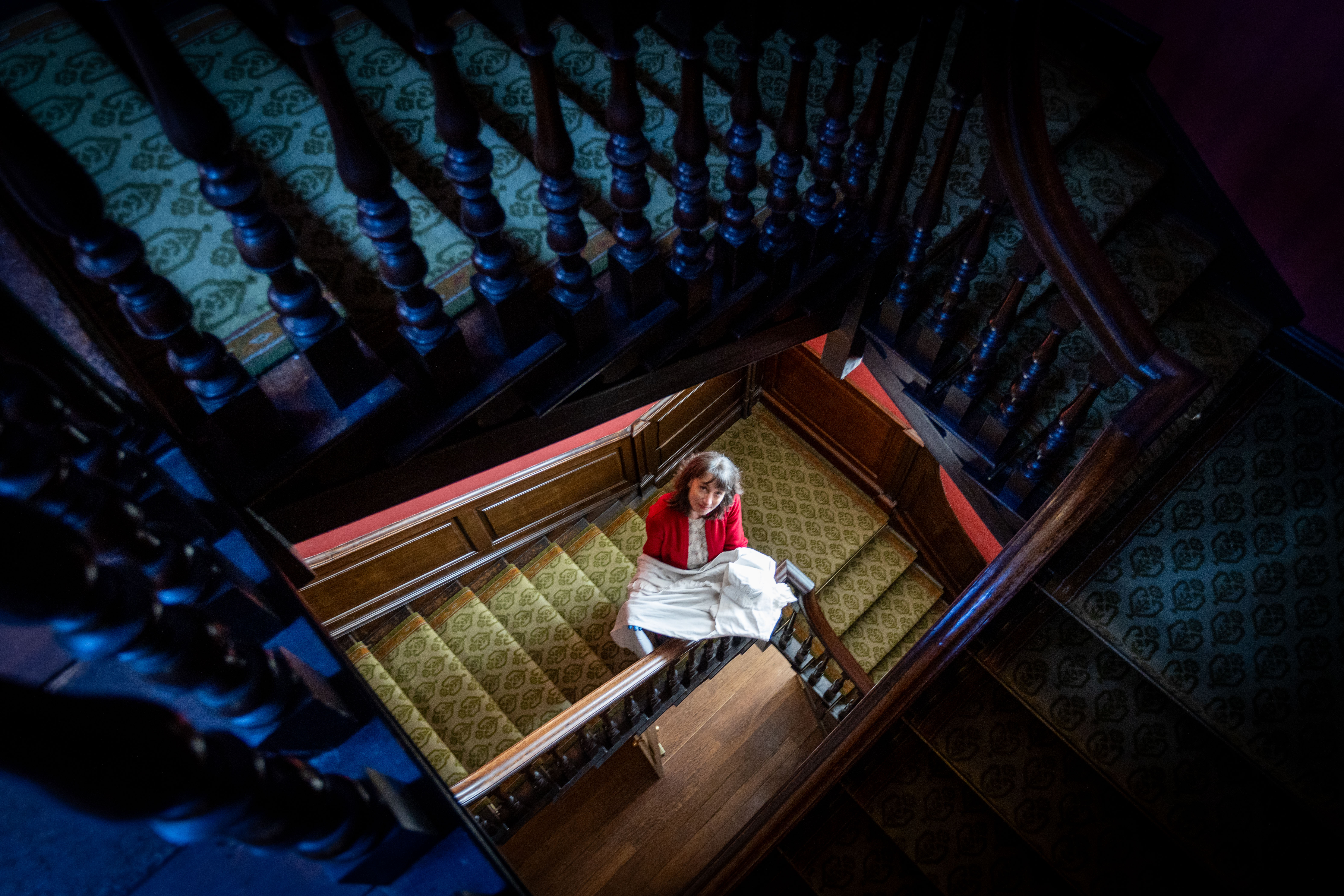 Curator Alexandra Loske carrying a nightgown up the stairs of Preston Manor.