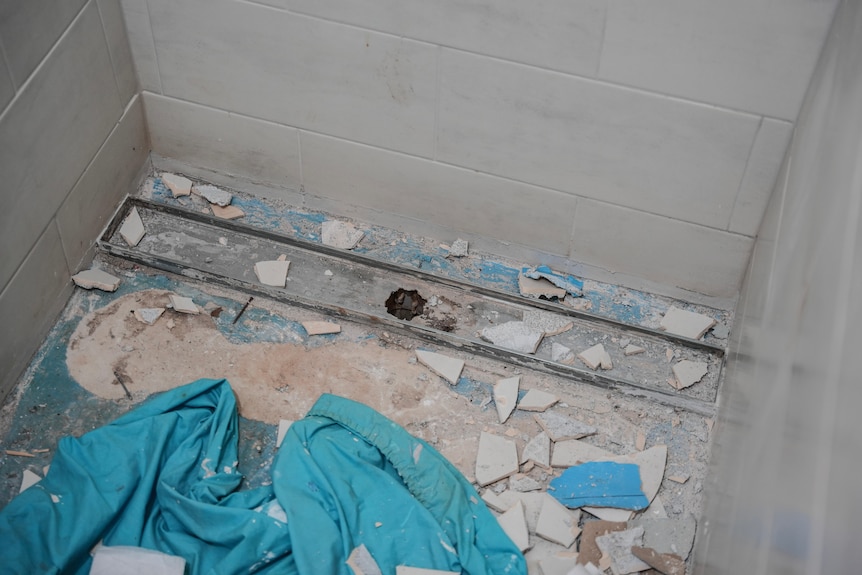The bottom of a shower with broken tiles.