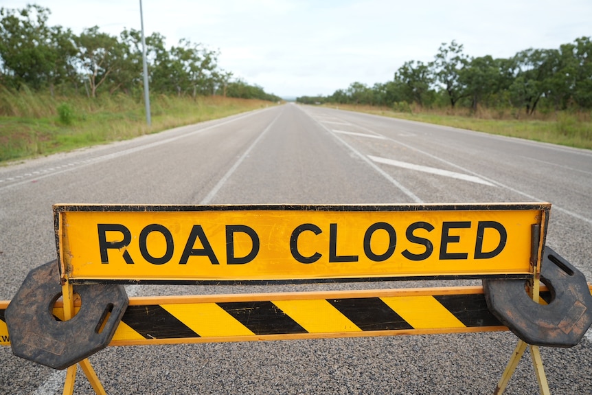 A yellow and black sign blocks part of a highway, the text reads: ROAD CLOSED
