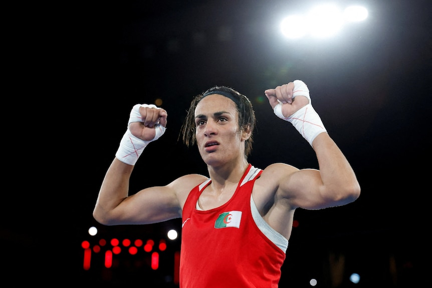 Imane Khelif of Algeria celebrates winning a boxing match, dressed in red outfit