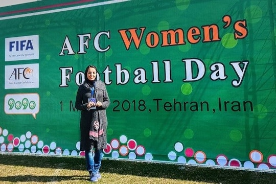 A girl poses in front of an AFC sign in a tournament in Iran in 2018.