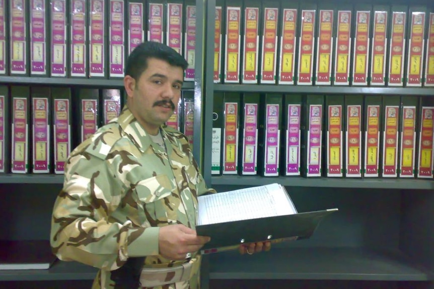 Ghanim Al Shnen in khakis reading a book in a library where khakis.
