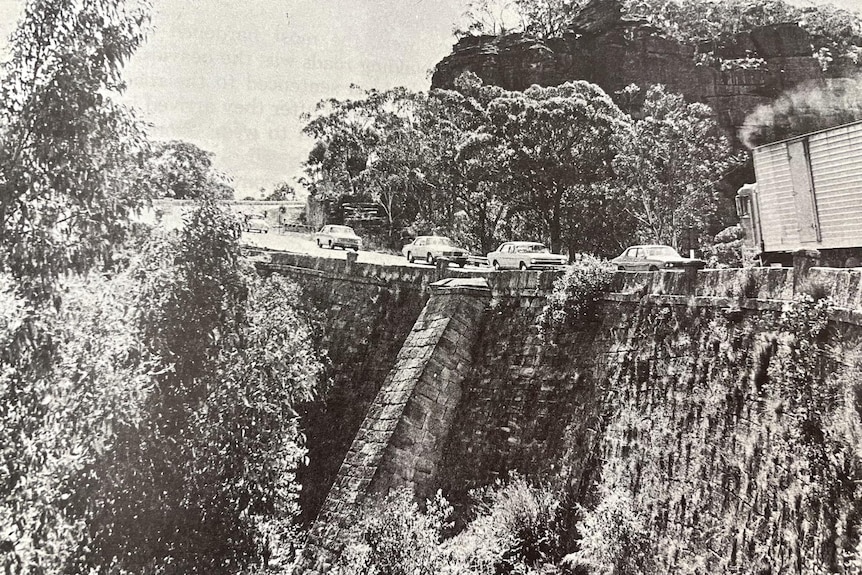 black and white photograph of cars driving over convict bridge