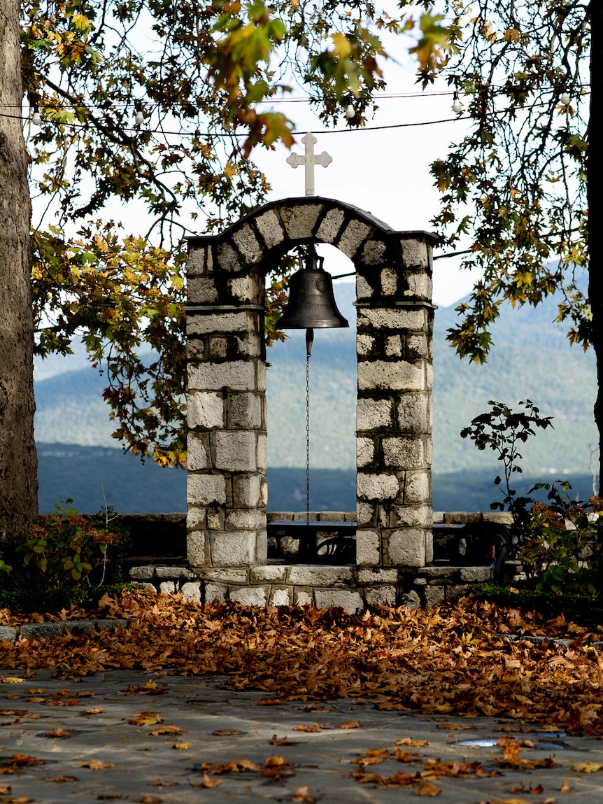 A bucket-sized bell hanging between stone pillars.