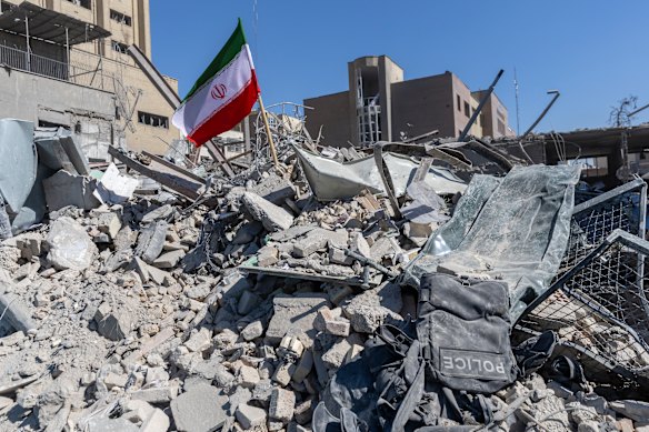 An Iranian flag is planted in the rubble of a police station in Tehran.