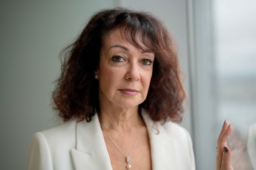 Woman in white blazer staring at camera