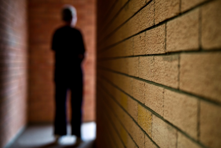 Deidentified person standing in hallway, moody lighting