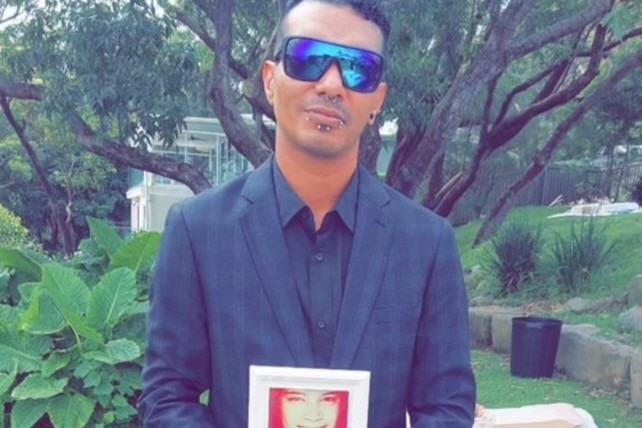 A young Indigenous man with sunglasses in a suit.