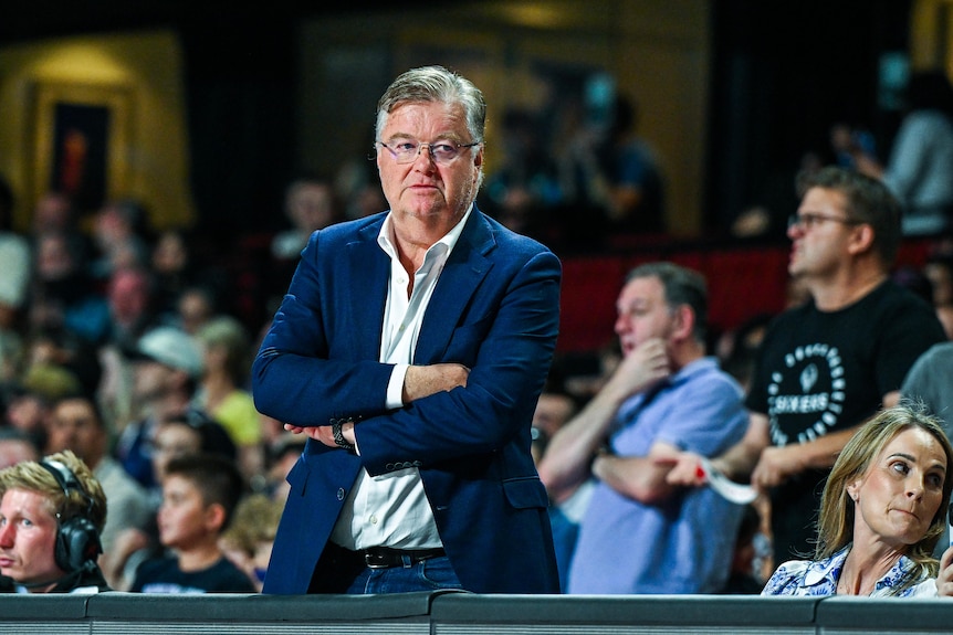 Grant Kelley crosses his arms while wearing a suit