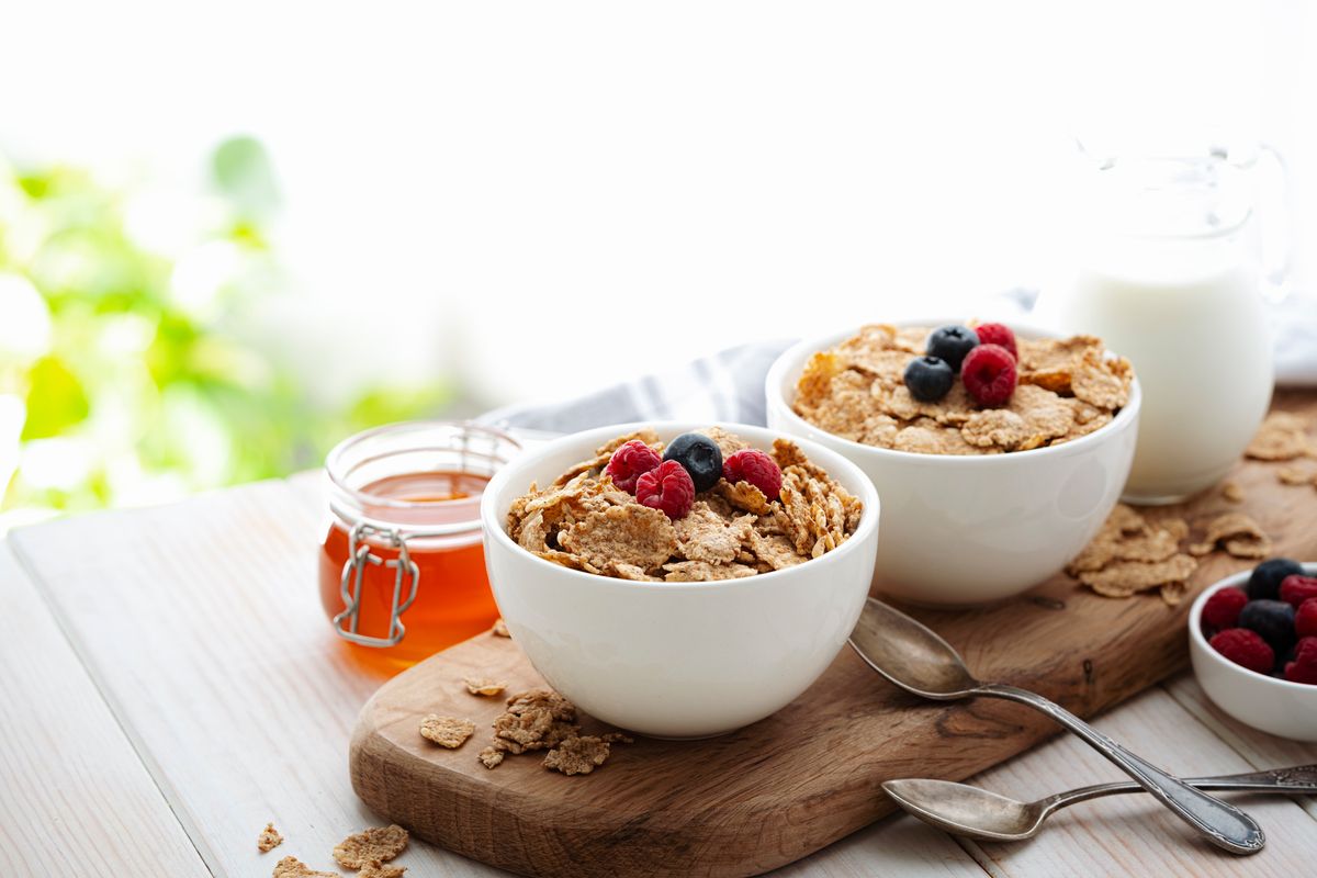 Two bowls filled with wholegrain corn flakes and berry fruits on a breakfast table. Breakfast cereal or healthy eating and dieting. Food high in dietary fiber