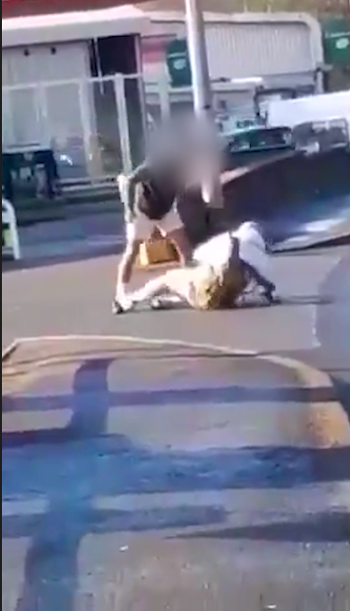 One man with his face blurred out standing over a man on the ground