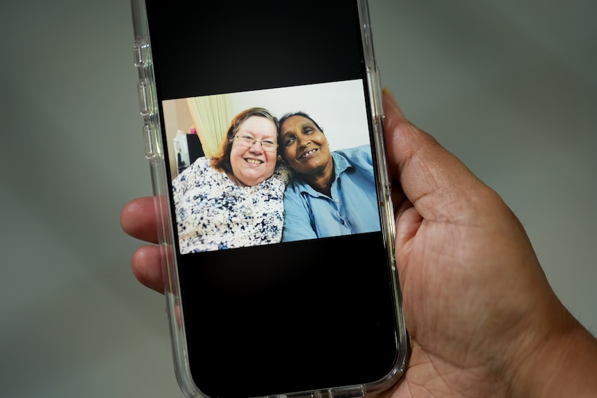 A person holding a phone with an image of Gabbie next to her adoptive mother.