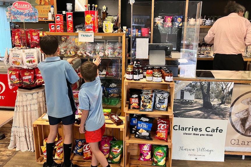 Two children look over the lolly rack at a regional general store.
