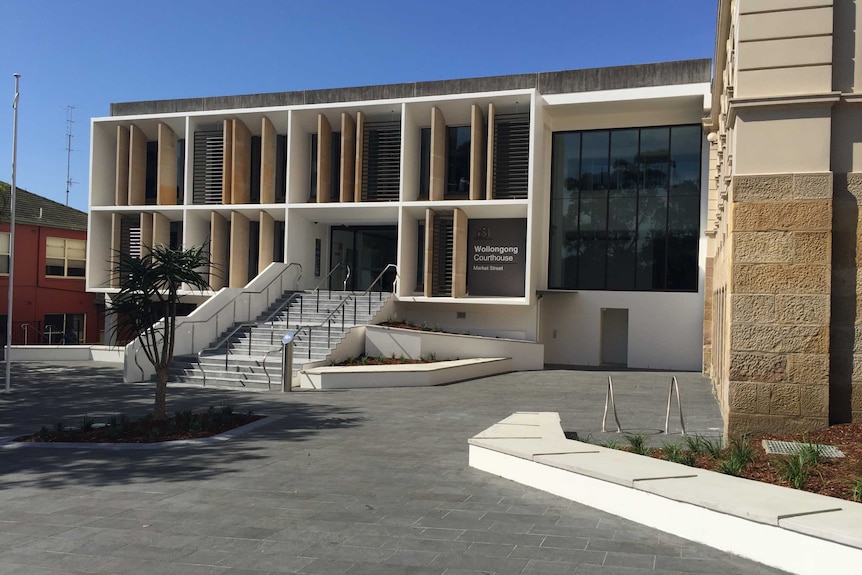 A modern, box-shaped court house with stairs leading up to the front entrance.