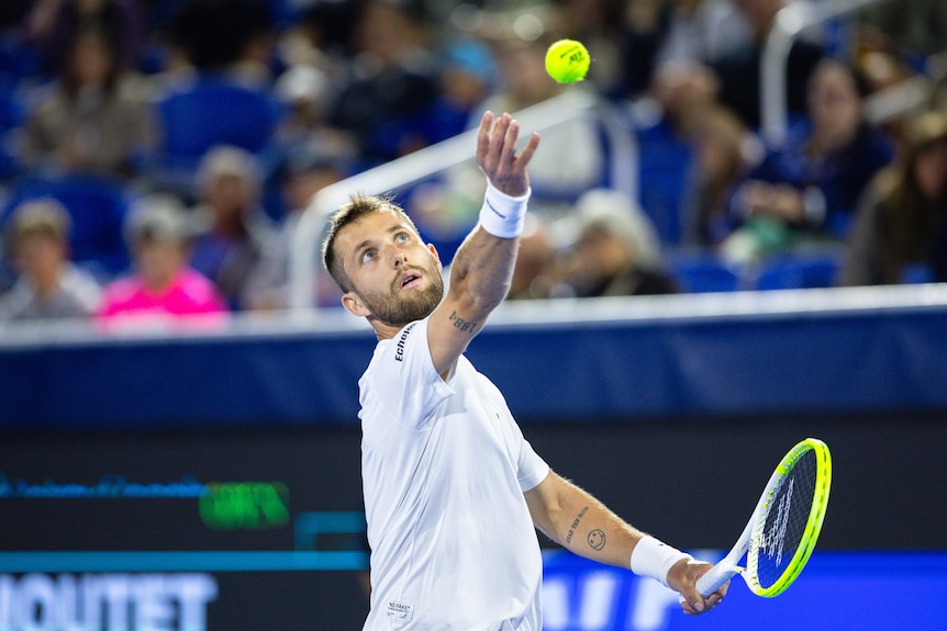 Corentin Moutet throws up his ball toss.