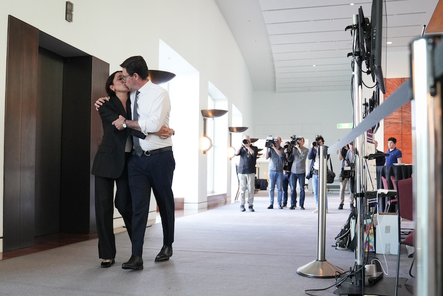 David Littleproud kisses his wife as they walk down a hall away from cameras.