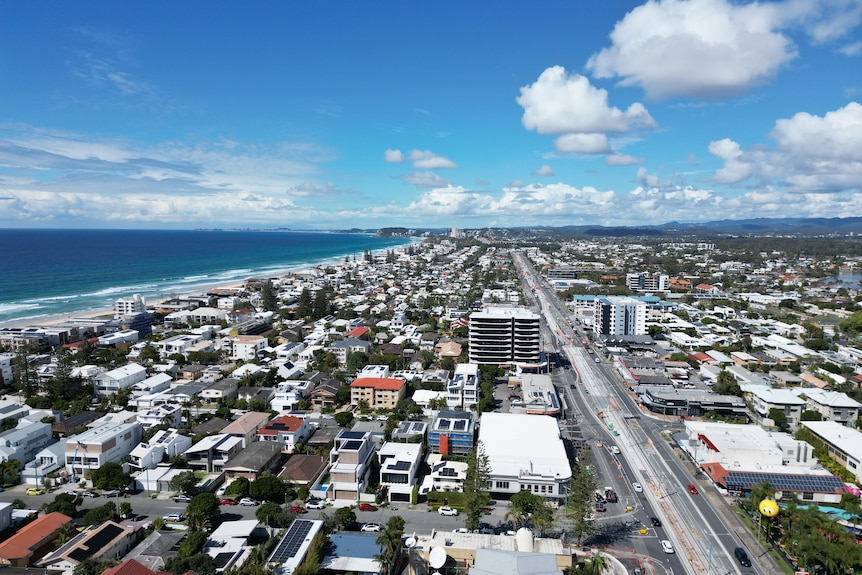 Low-storey buildings next to a major road, adjacent to a long beach on the left.