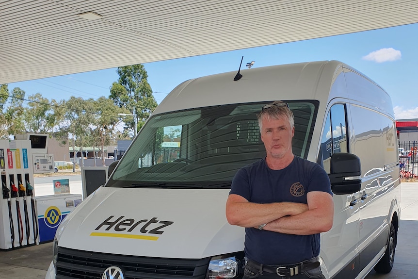 A man named Dennis standing next to his removal truck at a petrol station
